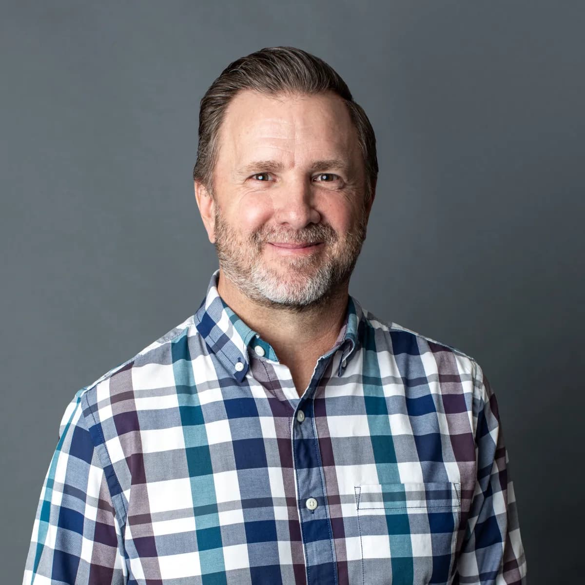 Marc Olsen, smiling, in a plaid button-down shirt